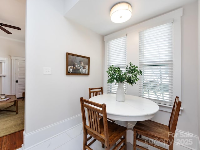 dining space with baseboards, ornamental molding, and a ceiling fan