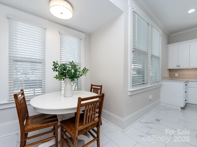 dining space with marble finish floor, a healthy amount of sunlight, baseboards, and ornamental molding