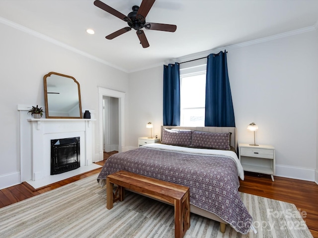 bedroom featuring a fireplace, crown molding, baseboards, and wood finished floors