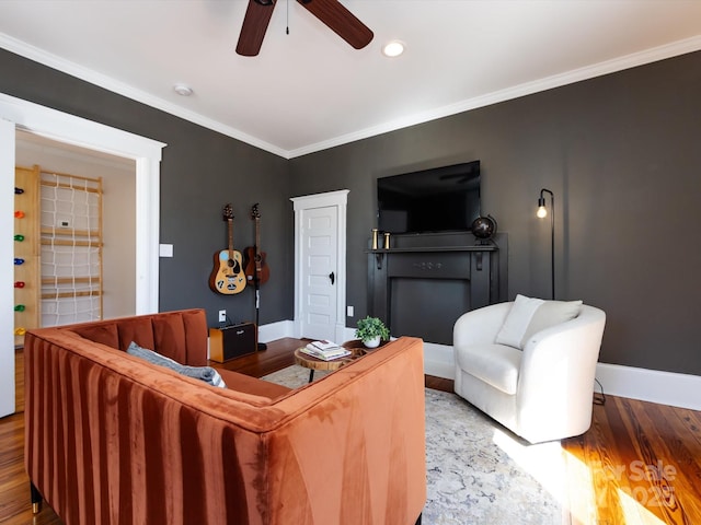 living room featuring baseboards, wood finished floors, ornamental molding, and a ceiling fan