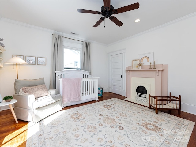 bedroom with visible vents, crown molding, baseboards, a fireplace with flush hearth, and wood finished floors