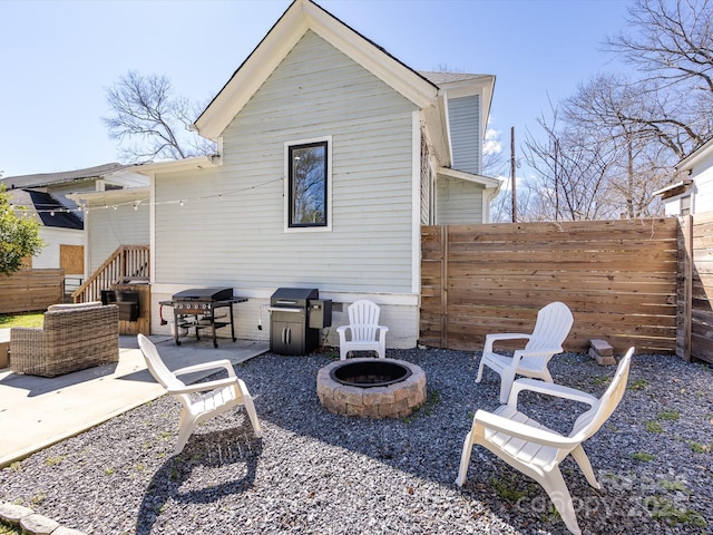 rear view of property with a patio area, a fire pit, and fence