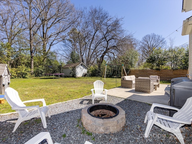 view of patio / terrace featuring an outbuilding, a fenced backyard, an outdoor living space with a fire pit, a storage shed, and a trampoline