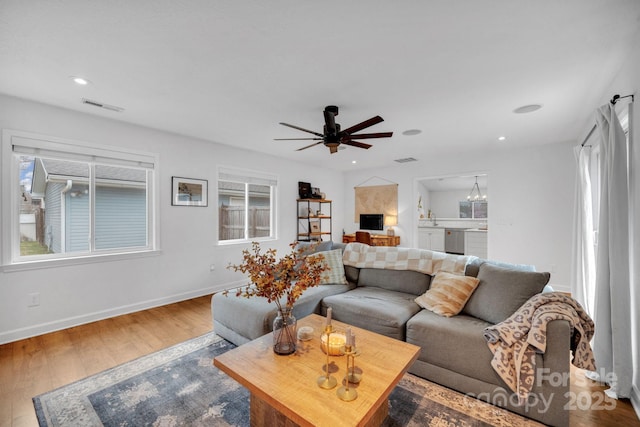 living area featuring wood finished floors, visible vents, baseboards, recessed lighting, and ceiling fan with notable chandelier