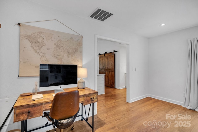 home office featuring visible vents, recessed lighting, a barn door, light wood-style floors, and baseboards