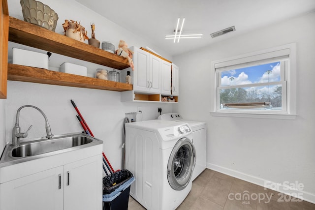 washroom with visible vents, a sink, baseboards, cabinet space, and separate washer and dryer