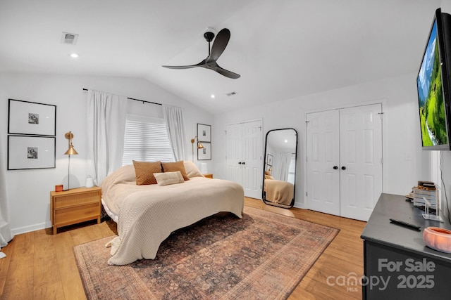 bedroom featuring lofted ceiling, visible vents, multiple closets, and light wood-type flooring