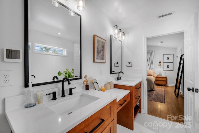 ensuite bathroom featuring visible vents, vanity, wood finished floors, and ensuite bathroom