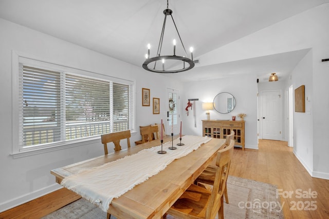 dining space with visible vents, light wood-style flooring, baseboards, a chandelier, and vaulted ceiling