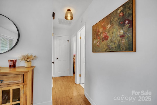 hall with visible vents, baseboards, and light wood-style floors