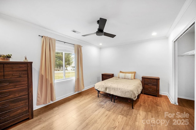 bedroom featuring wood finished floors, baseboards, visible vents, ornamental molding, and a closet