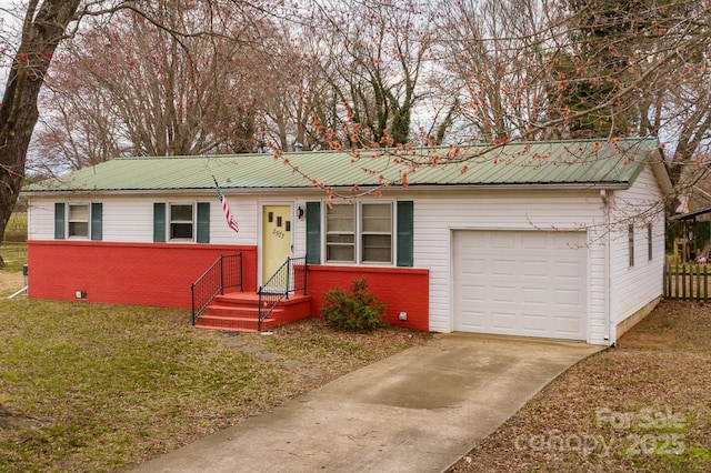 single story home with metal roof, brick siding, a garage, and driveway