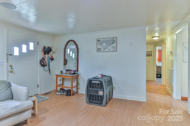 foyer entrance featuring baseboards, light wood-type flooring, and ornamental molding