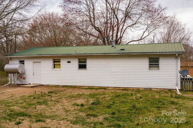 view of home's exterior featuring heating fuel, fence, a lawn, and metal roof