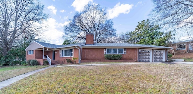 single story home featuring brick siding, a front yard, a chimney, driveway, and an attached garage