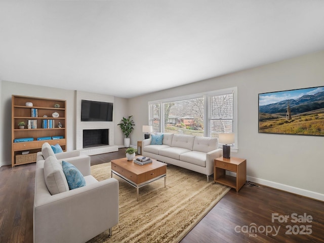 living area featuring a fireplace, baseboards, and wood finished floors