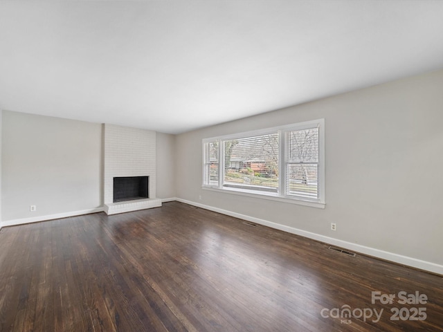 unfurnished living room featuring visible vents, a fireplace, baseboards, and wood finished floors