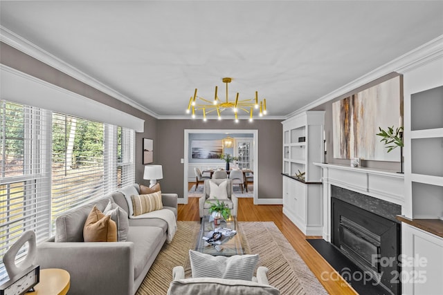 living area with a fireplace with flush hearth, light wood-style flooring, an inviting chandelier, crown molding, and baseboards