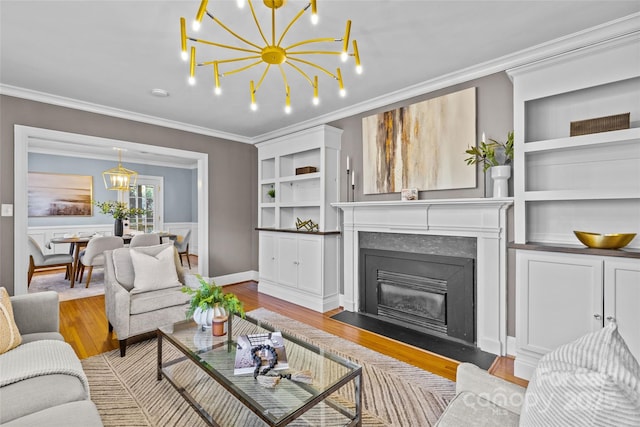 living room featuring wood finished floors, built in shelves, a chandelier, and ornamental molding