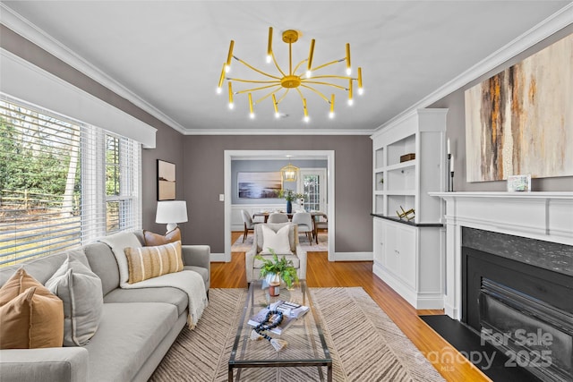 living area with a fireplace with flush hearth, a notable chandelier, light wood-style flooring, and crown molding