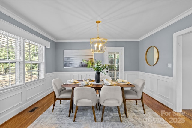 dining area with visible vents, plenty of natural light, light wood-style flooring, and an inviting chandelier