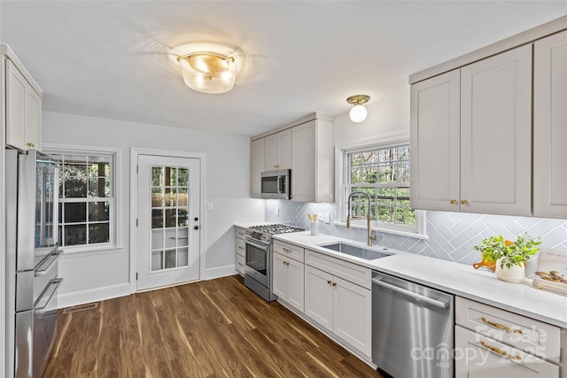 kitchen featuring dark wood-type flooring, a sink, tasteful backsplash, stainless steel appliances, and light countertops