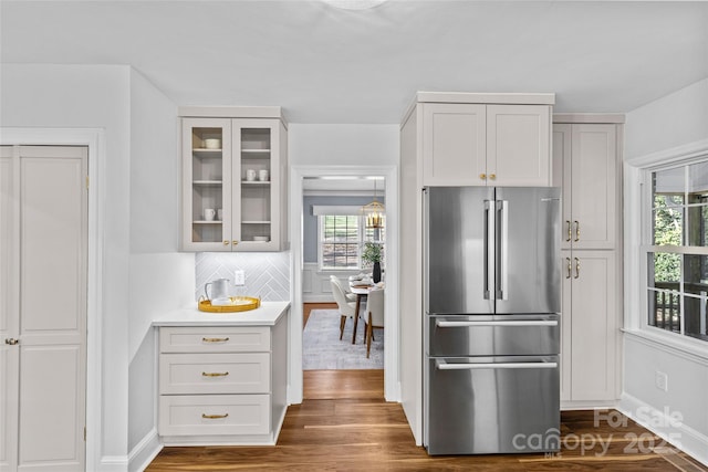 kitchen featuring dark wood finished floors, plenty of natural light, glass insert cabinets, and freestanding refrigerator