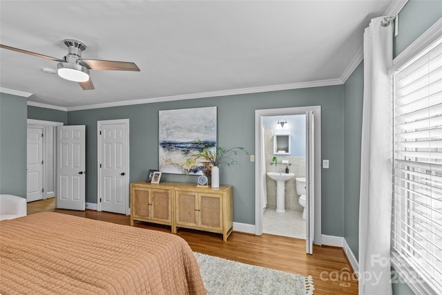 bedroom with ornamental molding, ensuite bathroom, baseboards, and wood finished floors