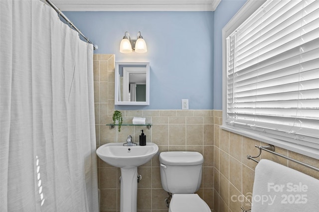 full bathroom featuring ornamental molding, wainscoting, curtained shower, tile walls, and toilet