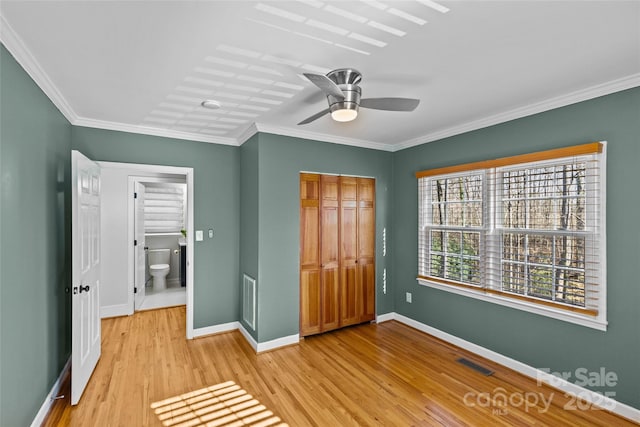 unfurnished bedroom with visible vents, crown molding, light wood-type flooring, and baseboards