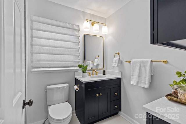 bathroom with toilet, vanity, and baseboards