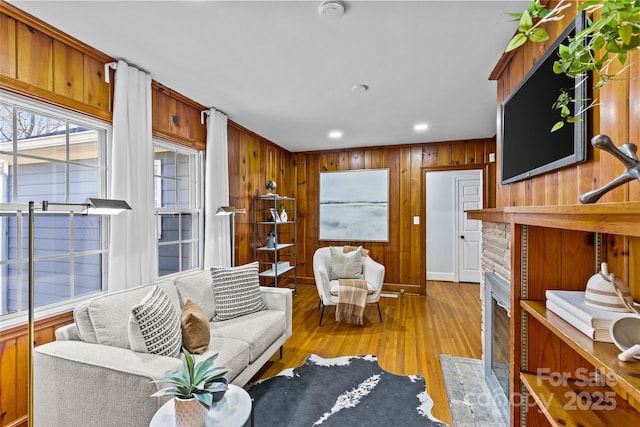 living room with wooden walls, recessed lighting, and wood finished floors