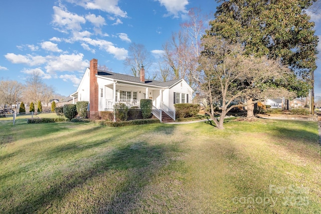 view of front of house with a porch, a chimney, and a front yard