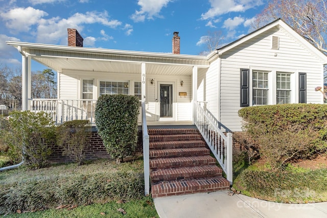 bungalow-style house featuring covered porch and a chimney