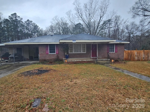 ranch-style house featuring a carport, fence, brick siding, and a front lawn