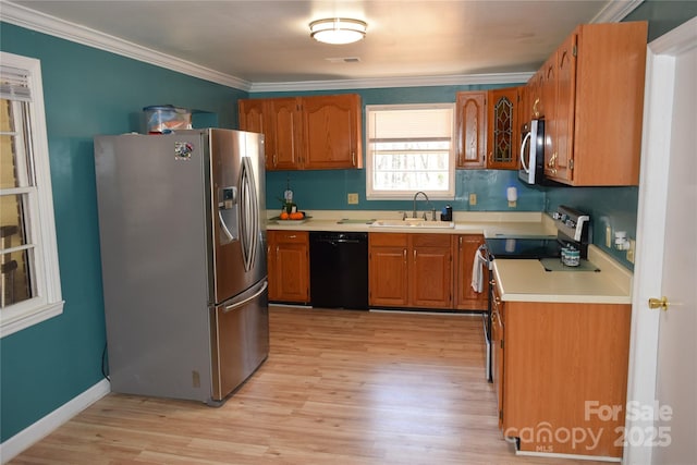 kitchen with ornamental molding, stainless steel appliances, light countertops, and a sink