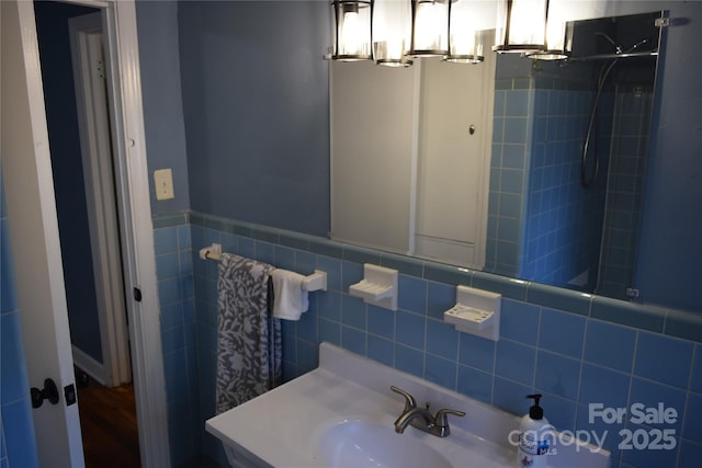 bathroom with tile walls, a wainscoted wall, and a sink