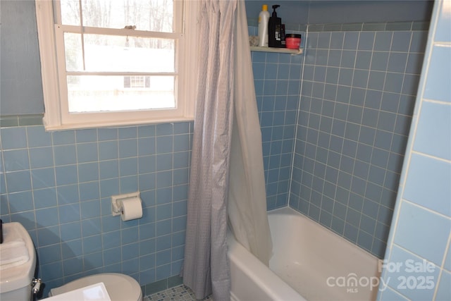 full bathroom with tile walls, toilet, and shower / tub combo with curtain