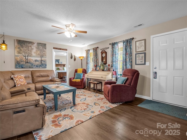 living room featuring visible vents, a ceiling fan, a textured ceiling, wood finished floors, and baseboards