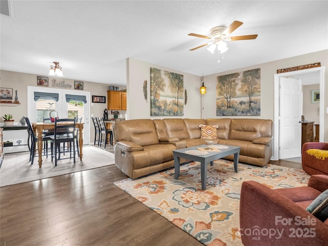 living room with visible vents, a textured ceiling, wood finished floors, and a ceiling fan