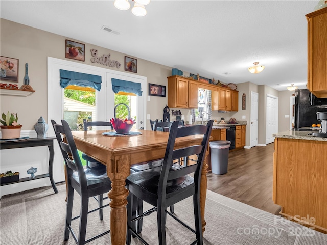 dining room featuring plenty of natural light, wood finished floors, visible vents, and baseboards