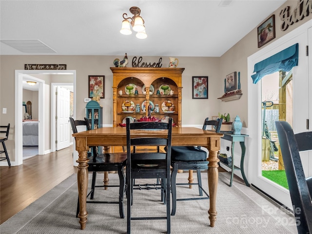 dining room featuring wood finished floors, visible vents, and baseboards