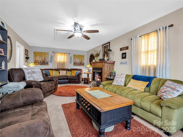 living room featuring a glass covered fireplace, a ceiling fan, and light carpet