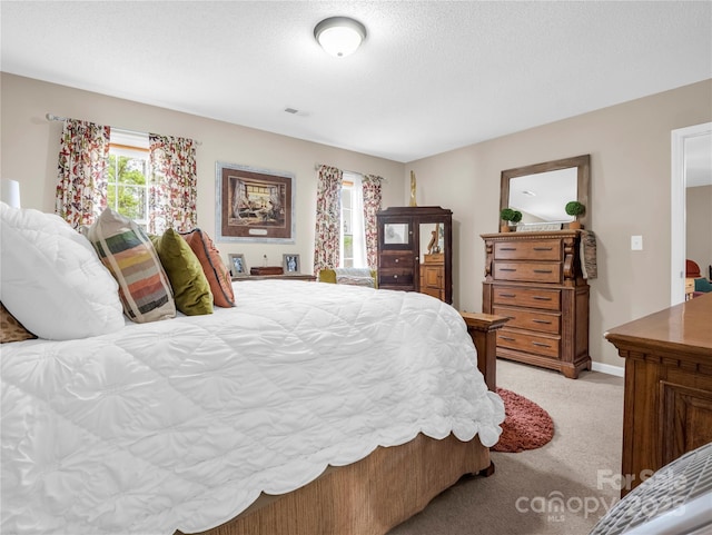 bedroom with light colored carpet, baseboards, and a textured ceiling