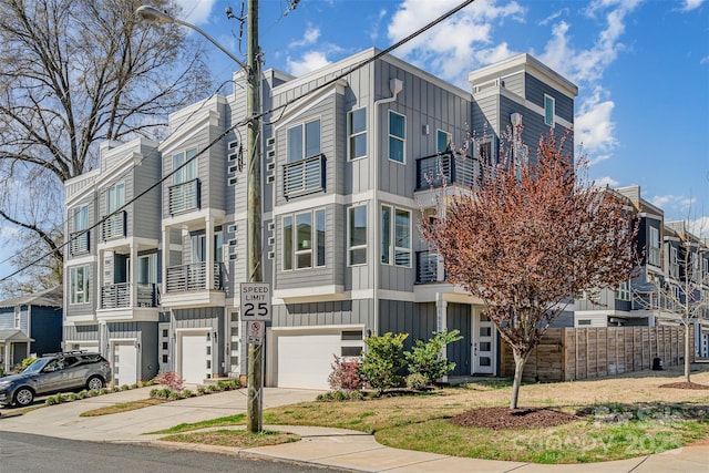 exterior space featuring board and batten siding, an attached garage, a balcony, and driveway