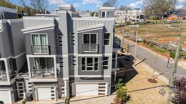 view of front facade featuring board and batten siding, an attached garage, a balcony, and concrete driveway