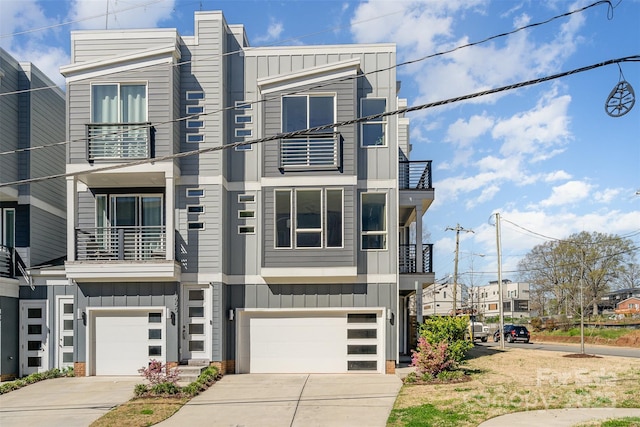 view of front of home featuring board and batten siding, an attached garage, driveway, and a balcony
