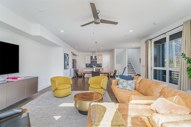 living area featuring wood finished floors, stairs, ceiling fan, baseboards, and recessed lighting