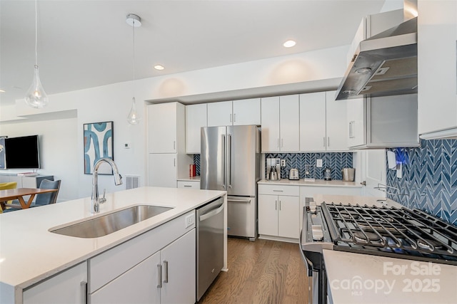 kitchen with stainless steel appliances, a sink, dark wood-style flooring, extractor fan, and light countertops