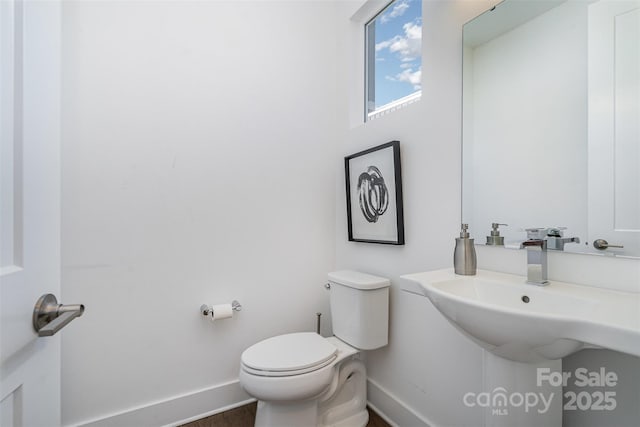 half bath with baseboards and toilet